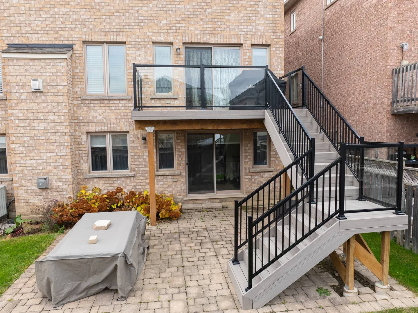 Elevated grey deck with a broad stair flight, black picket stair guards and glass panels around the landing.
