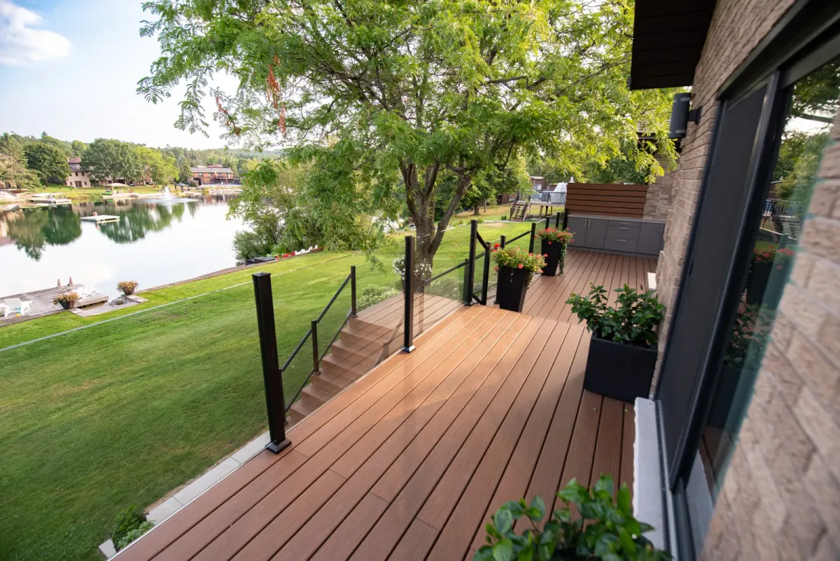 Lakefront project with a two-level composite deck, glass railings and an outdoor kitchen.