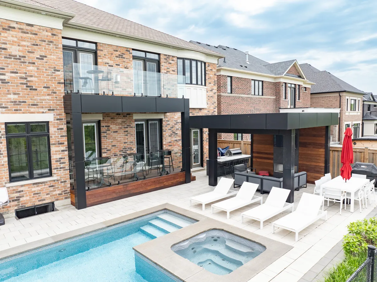 Ipe-clad poolside terrace with an upper glass-railed balcony and covered lounge