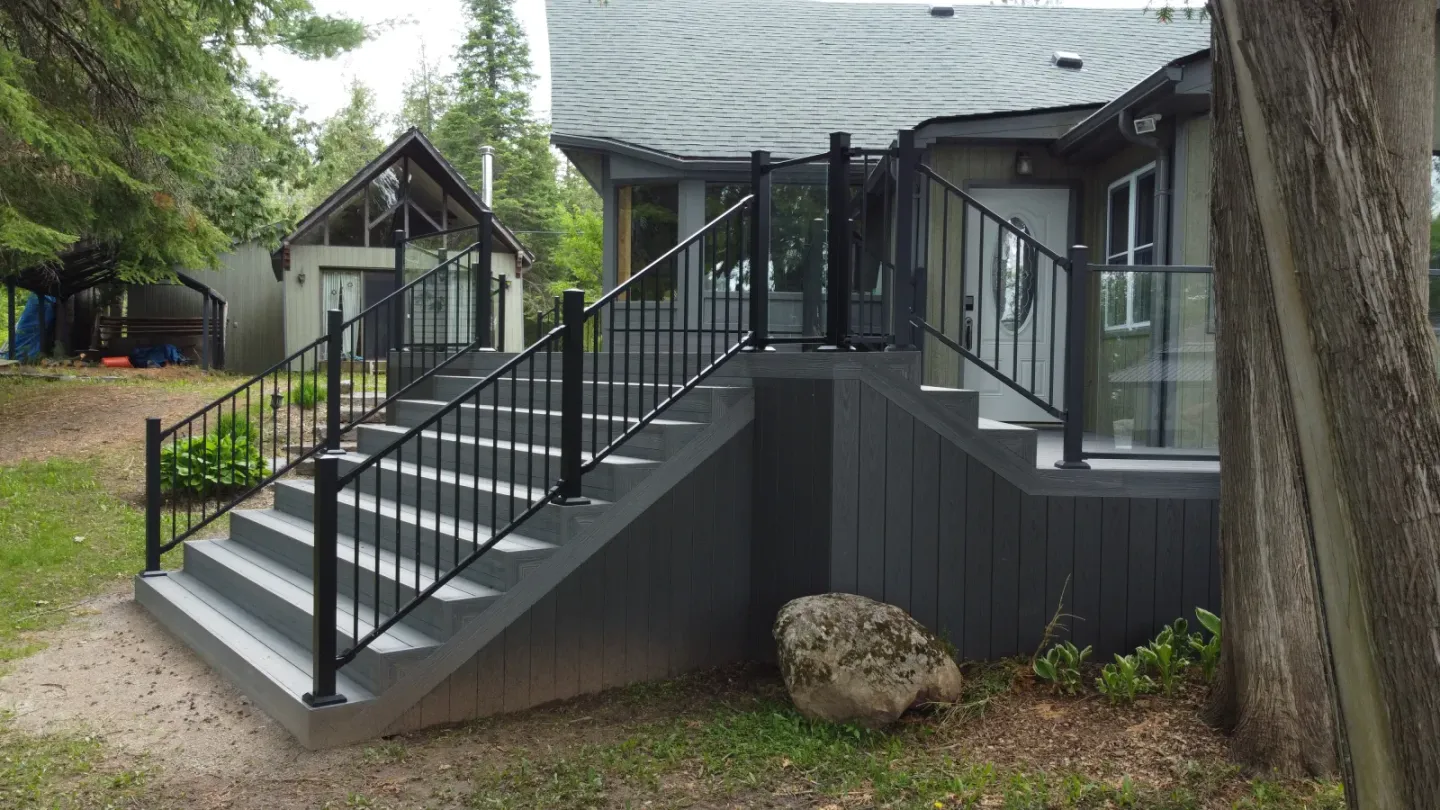 Finished Kawartha Deck Builders project with a wide composite staircase, aluminum rails, and glass panels
