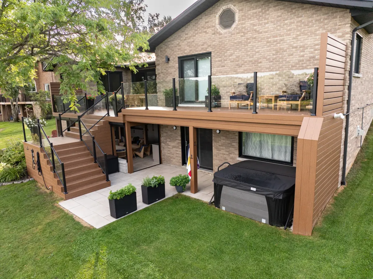 Finished two-level composite deck with glass railings and stairs on an Ontario home