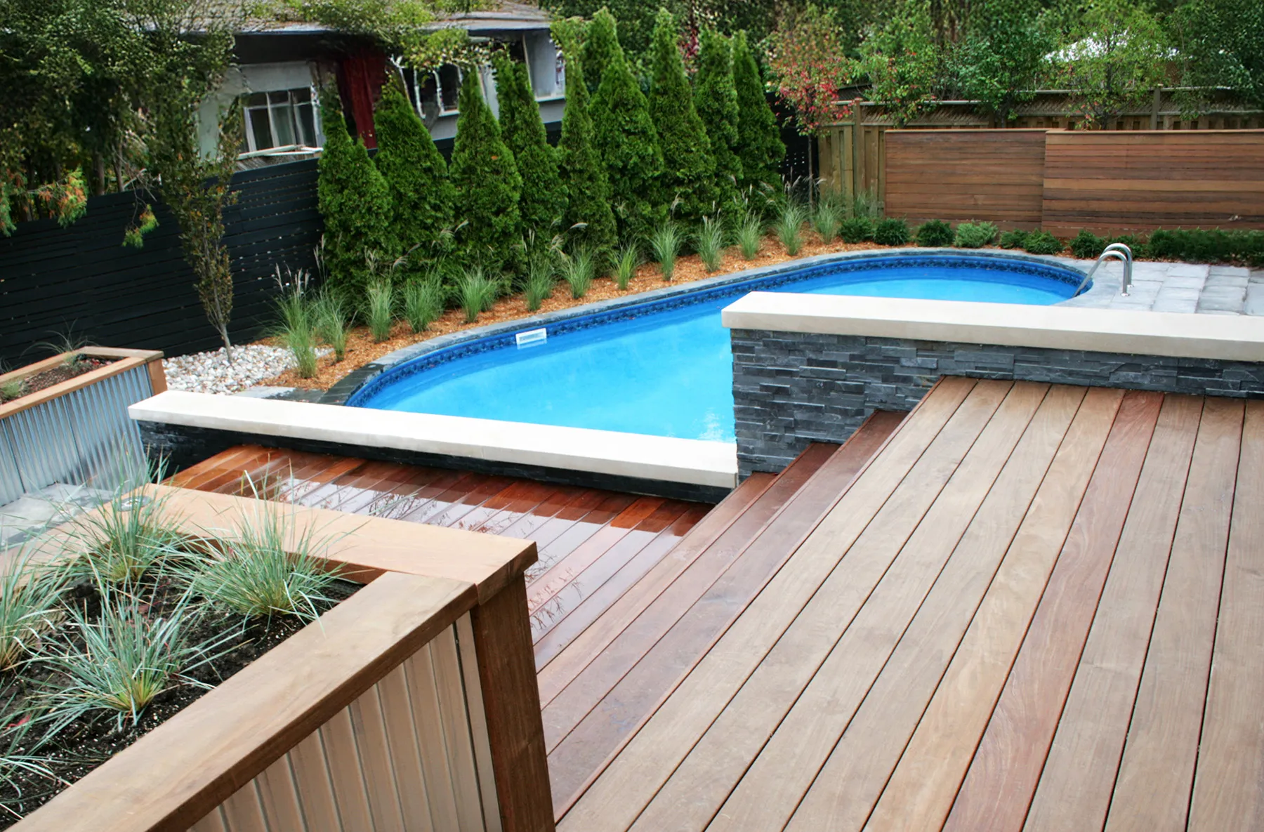 Wood deck meeting a pool surround, planted beds and changes in level