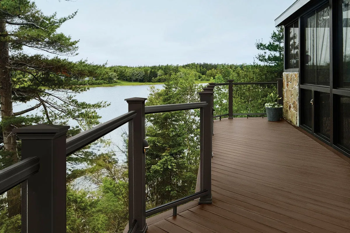 TimberTech deck in richly hued brown boards attached to a lake house on the water.