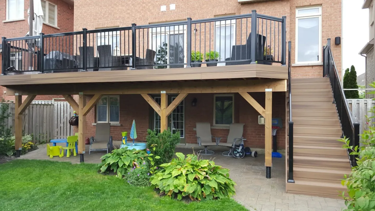 Framing of an elevated backyard deck under construction, showing joists, beams and the open ventilated space below the deck surface
