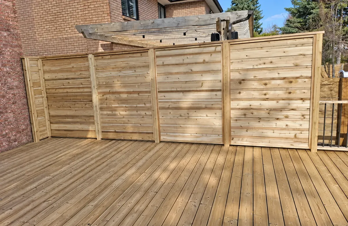 Pale, low-knot softwood deck boards with matching horizontal privacy screens on a finished backyard project.